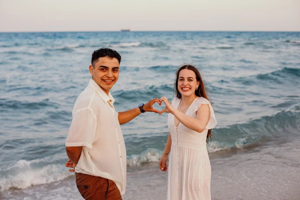 Couple Making Heart with Hands on Beach