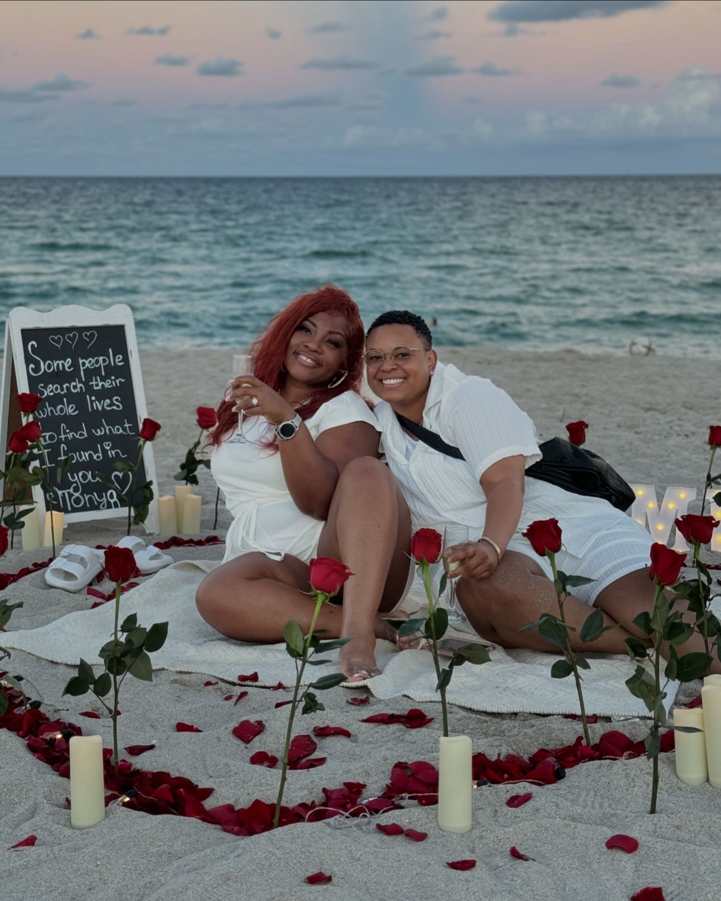 Beach proposal with candles and roses and custom sign