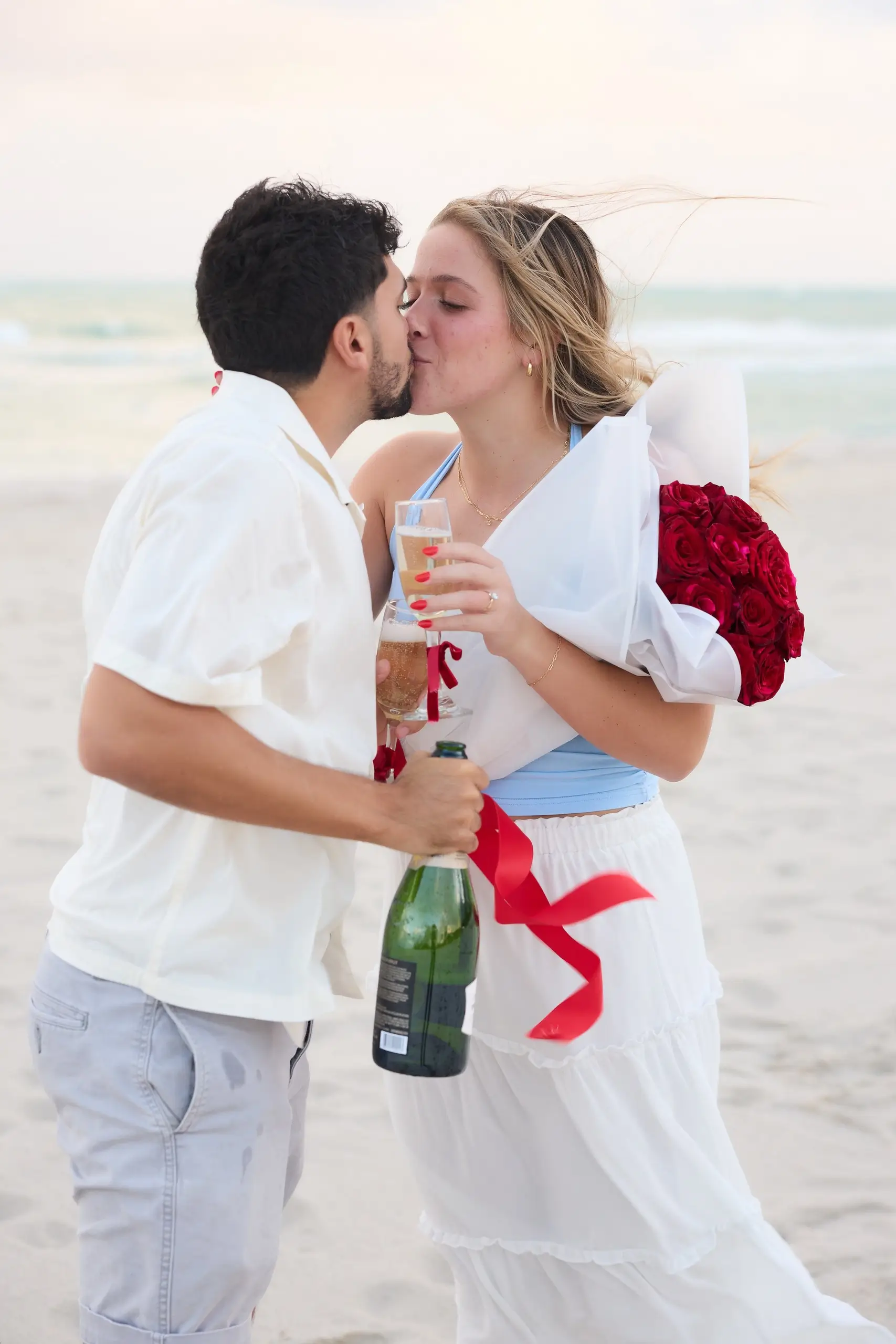 Couple kissing with champagne - beach proposal