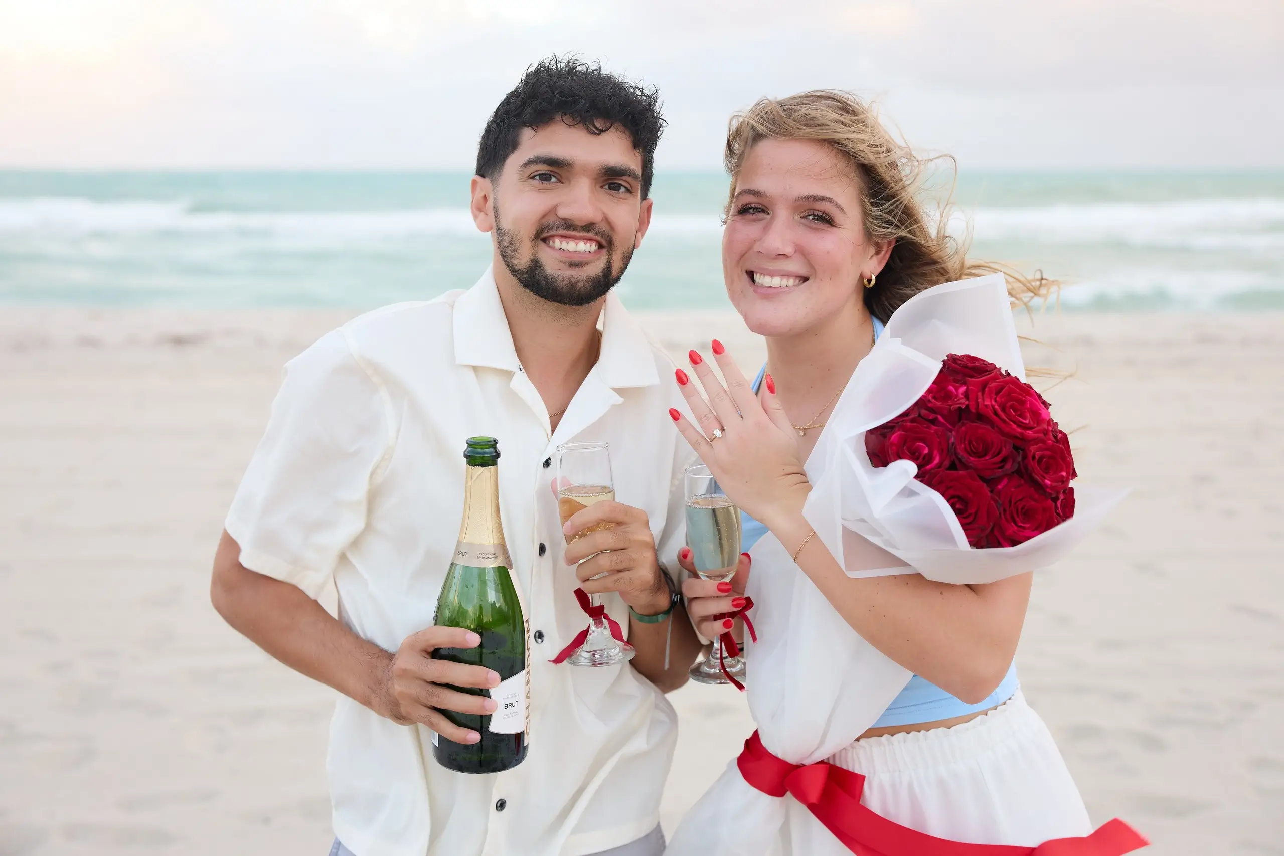 Couple showing off ring - beach proposal