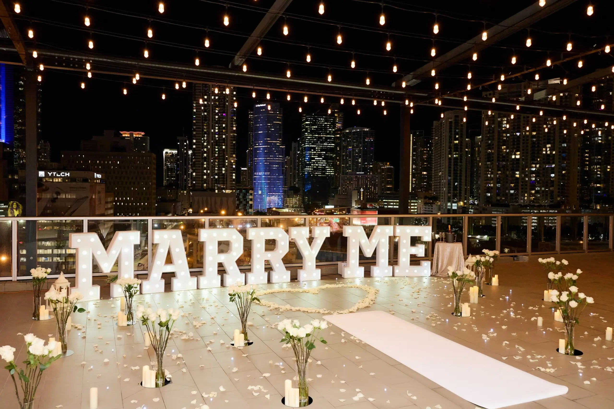 Miami Rooftop proposal setup with lights and flowers and carpet.