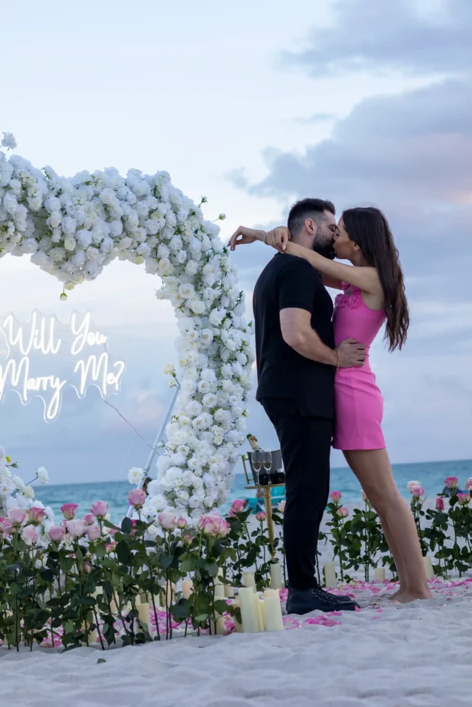 Miami Beach Proposal - Kiss with Marry Me Sign background with white rose hear and candles/flowers